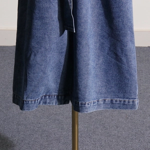 Detailed close-up of a long denim trench coat showing stitching and fabric texture