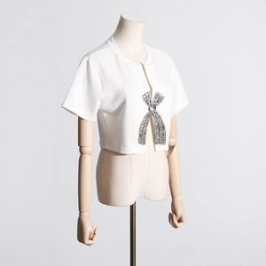 Detail shot of white short sleeve top featuring rhinestone bow buttons on a wooden mannequin