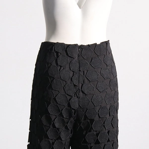 Detail of black high-waisted pants with hexagonal hollow embroidery and invisible zipper