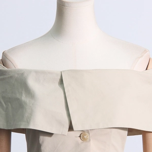 Détail d'un élégant haut beige à épaules dénudées avec revers large et bouton central