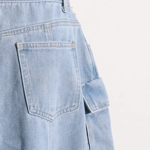 Detail of light blue washed denim skirt with functional cargo pockets and double stitching