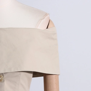 Détail du haut beige à épaules dénudées avec texture tissée et col à bouton élégant