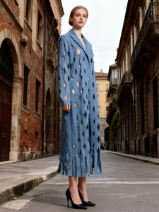 Long blue denim trench coat with hollow diamond patterns and fringe details in street style