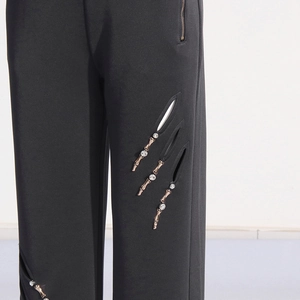 Detail der schwarzen High-Waist-Hose mit strassbesetzten Ausschnitten in Knochenform