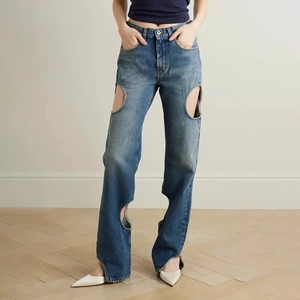 Gros plan d'un jean taille haute à jambe droite avec découpes circulaires et denim délavé