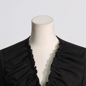Detail of the elegant V-neckline with delicate pleated ruffles on a black blazer