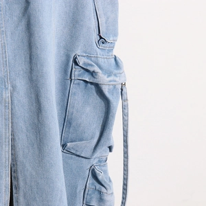 Detail view of cargo pocket with flap and long decorative strap on light blue denim skirt