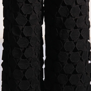 Detail of black pants featuring hexagonal honeycomb lace embroidery and hollowed-out texture