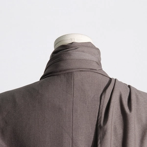 Detail shot of structured high-neck collar and shoulder tailoring on taupe blazer