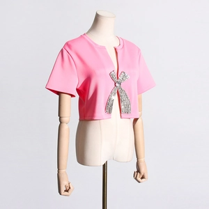 Close-up of sparkling rhinestone bow embellishment on vibrant pink short sleeve top