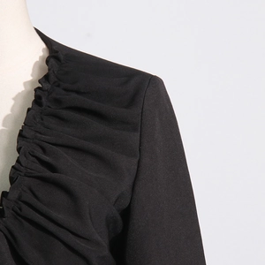 Detailed view of the pleated V-neckline and woven fabric on the black blazer