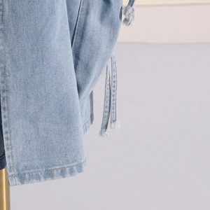 Close-up of light blue denim fabric texture with drawstring and fringe detail