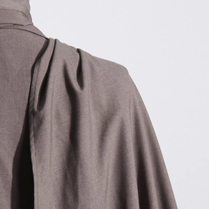 Detail of tailored shoulder seam and textured twill fabric on a dark brown blazer jacket