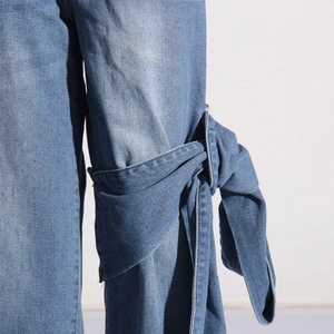 Détail du nœud en denim cousu sur le côté du jean bleu clair à taille haute et jambe large