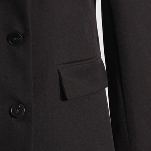Detail shot of black blazer with resin buttons and a neat flap pocket on textured fabric