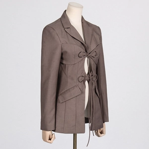 Detail of taupe blazer featuring structural stitching and tie-up drawstring waist closure