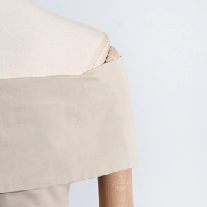Gros plan sur le pli élégant de l'épaule dénudée et la texture fine du haut beige