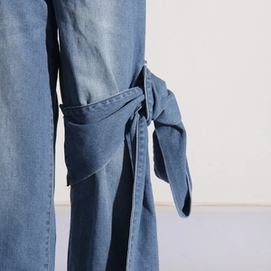 Détail du jean bleu clair avec patchwork de nœuds élégants sur le côté du pantalon
