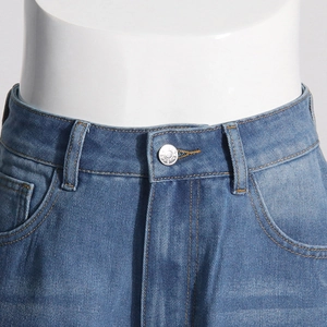 Détail de la taille d'un jean bleu à taille haute avec bouton argenté et coutures orange