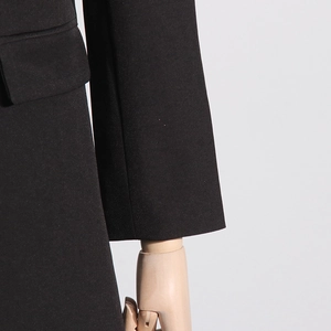 Detailed view of the flap pocket and sleeve cuff on a black fitted blazer jacket
