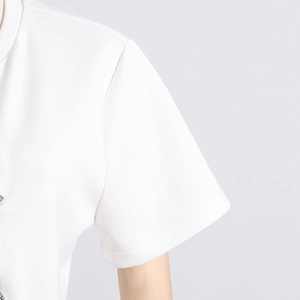 Detailed close-up of white t-shirt shoulder with rhinestone bow and knit texture