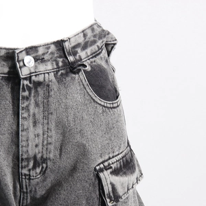 Detail of gray washed denim cargo pants showing metal button and side flap pocket