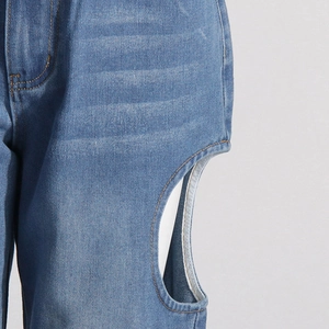 Détail de jean bleu taille haute avec découpe latérale design et surpiqûres jaunes nettes