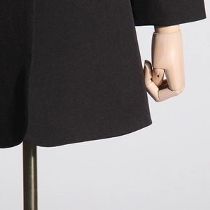 Close-up of premium black blazer fabric texture with smooth stitching and refined finish
