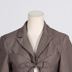 Detail of dark brown blazer top featuring V-neck tie-front bow and lapel collar design