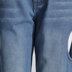 Gros plan détaillé d'un jean en denim bleu clair avec des découpes circulaires latérales
