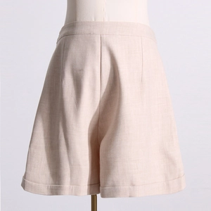 Détail d'un short taille haute en lin avec revers et plis sur le devant en beige avoine