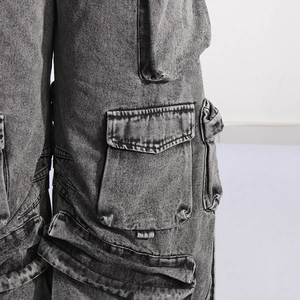 Detail of dark gray acid wash denim cargo pants featuring large side flap pockets