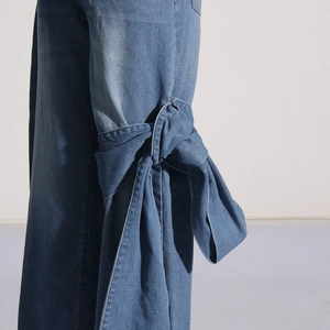 Détail de côté du jean taille haute avec grand nœud papillon décoratif en denim