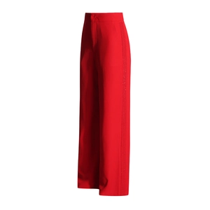 Detail view of red high-waisted trousers with decorative side trim and smooth suit fabric