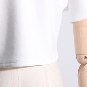 Detailed close-up of double-needle hem stitching on a white designer cotton t-shirt