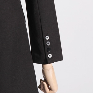 Detail of black blazer sleeve showing four stacked buttons and premium tailoring texture