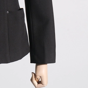 Close-up of black blazer fabric featuring a minimalist pocket with silver metal rivet detail