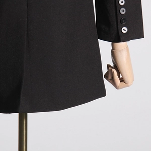 Detail of grey cuff buttons and smooth black fabric on a premium women's blazer jacket