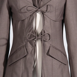 Detail of dark grey blazer featuring tie-knot front closure and hollow-out waist design