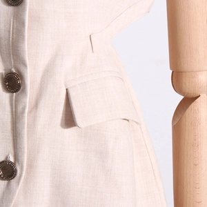 Vue détaillée du gilet beige avec boutons métalliques gaufrés vintage et poche latérale