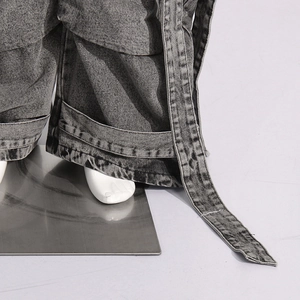Detailed macro view of grey washed denim fabric with decorative ribbon on cargo jeans