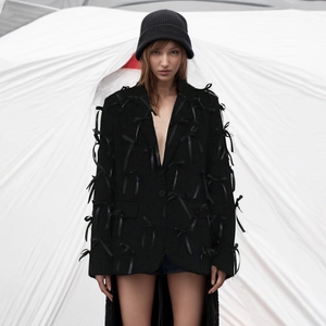 Detailed close-up of 3D satin bow decorations on a black oversized women's blazer jacket