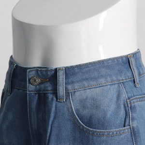 Détail de la taille du jean bleu avec bouton métallique et poches classiques courbées