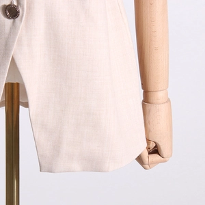 Détail du blazer beige en sergé avec un bouton marron vintage à bordure métallique