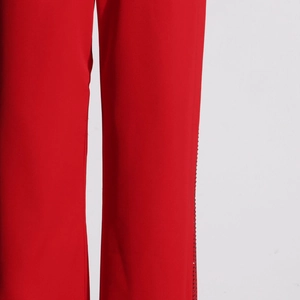 Detail view of red high-waist straight-leg trousers with sparkling rhinestone side seam trim