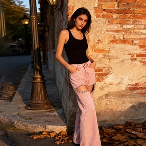 Detail der rosa High-Waist-Jeans mit weitem Bein, Cut-Out und Herz-Kettenanhänger
