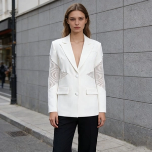 Dettaglio del blazer bianco con eleganti inserti in pizzo sulle maniche e tessuto solido