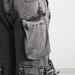 Detail of dark grey cargo jeans featuring large side flap pockets and retro wash texture