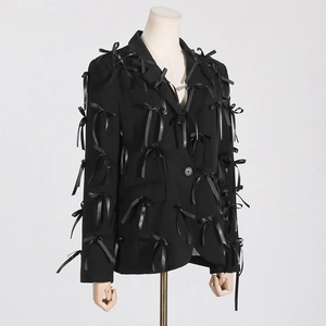 Detailed view of the 3D black silk ribbon bows stitched onto a structured blazer
