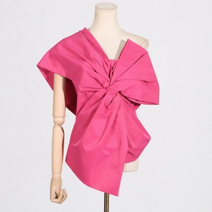Detail of rose red off-shoulder top featuring a large decorative bow and pleated texture